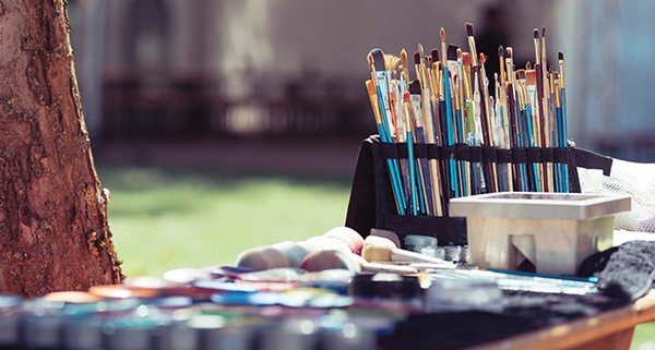 Paintbrushes and other painting supplies on a table outside in a park